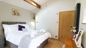 A bedroom with a bed, bedside table, and a wooden door. - Sunnybrook Cottage (Clitheroe)