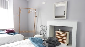 A bedroom with two beds, a wooden wardrobe, a mirror, and a fireplace. - Todlaw Farm House (Jedburgh)