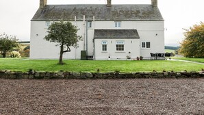 A white two-story house with a stone wall in front, a gravel driveway, and a tree in the yard. - Todlaw Farm House (Jedburgh)