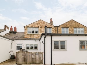 A two-story stone house with a white exterior and a wooden fence. - Canny Cottage (Belford)