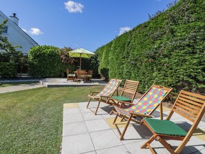 Eine Terrasse mit Gartenmöbeln, einem Tisch und Stühlen.