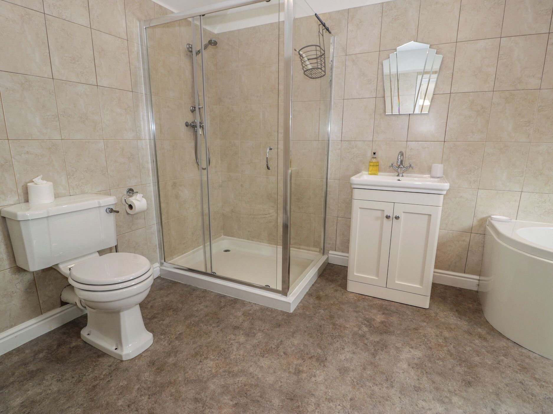 Une salle de bain comprenant des toilettes, un espace douche, un lavabo et un miroir.