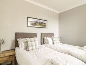 A hotel room with two beds, a nightstand, a lamp, and a framed picture on the wall. - Ivy Bank (Windermere)