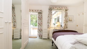 A bedroom with a bed, a dresser, a mirror, and a window with curtains.
