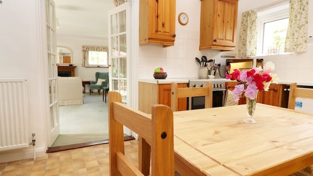 A kitchen with wooden cabinets, a dining table with chairs, and a vase with flowers.