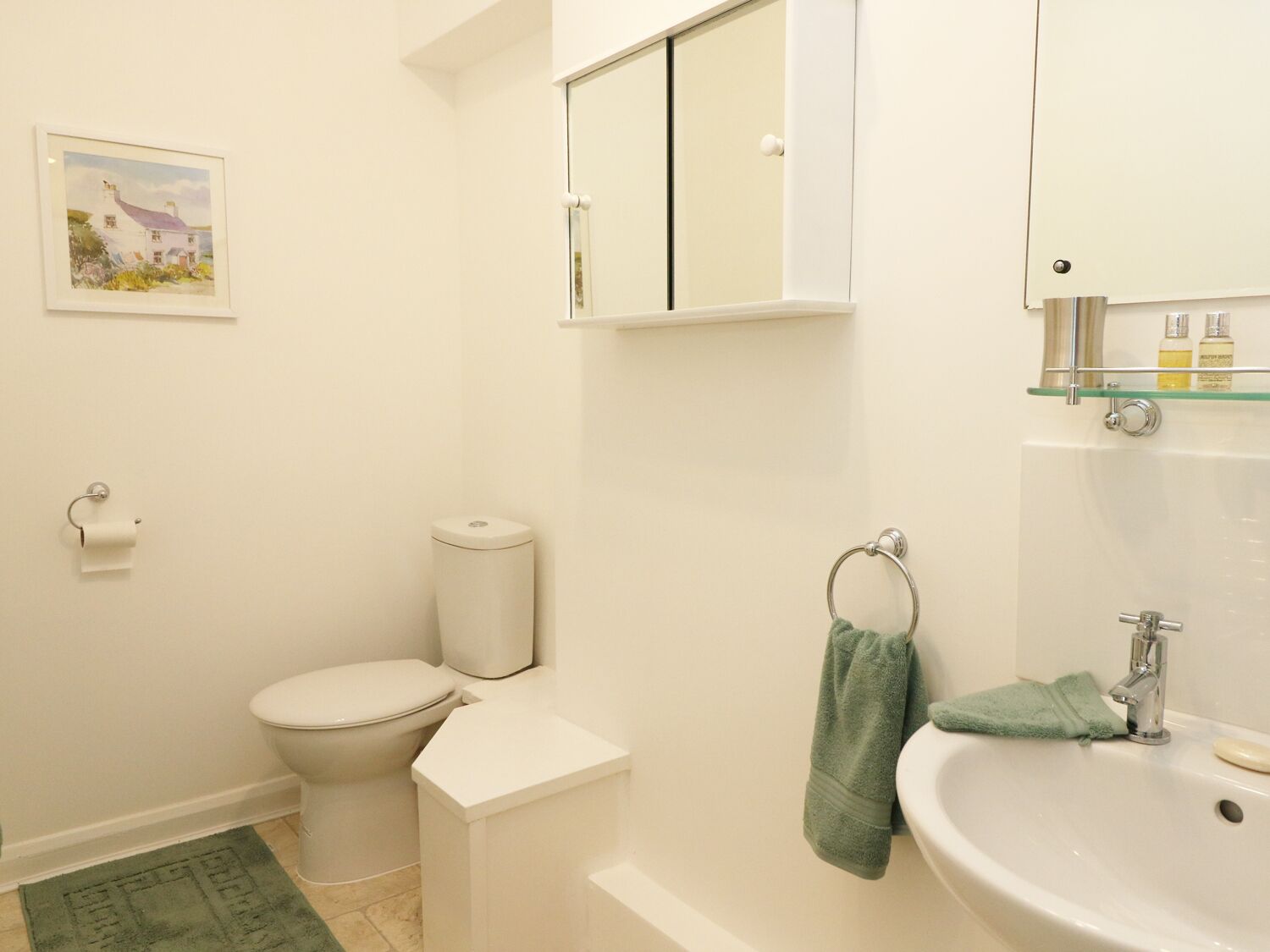 A bathroom with a toilet, sink, and a small mirror.