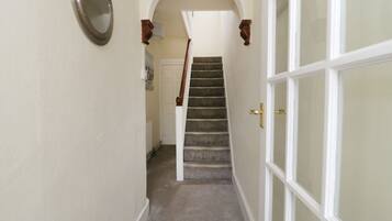 A hallway with a carpeted staircase leading to a door with glass panels.