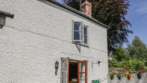 A white house with a wooden bench and a table outside. - The Cottage (Llangollen)