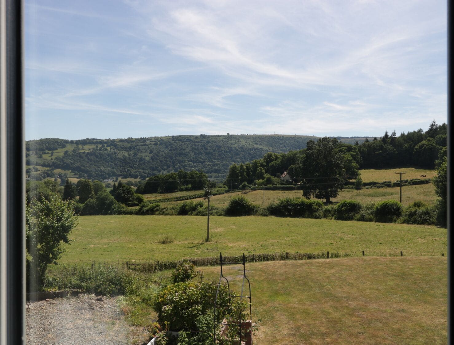 A view of a rural landscape with rolling hills, a clear sky, and a distant tree line.