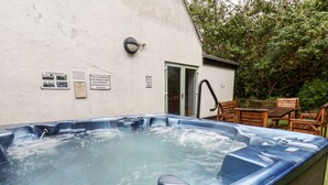 Una vasca idromassaggio con un pontile in legno e sedie, circondata da un muro bianco con cartelli.