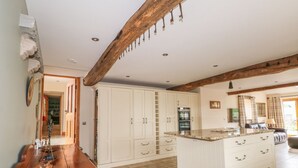 A spacious kitchen with a central island, white cabinetry, and a stone wall. - Rose Hips Barn (Chorley)