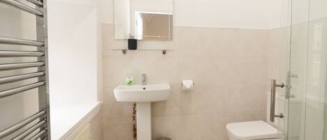A bathroom with a white sink, mirror, and toilet.
