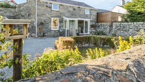 A stone house with a stone wall, a wooden deck, and a gravel driveway. - Y Cilgwyn (Blaenau Ffestiniog)