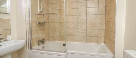 A modern bathroom with a glass-enclosed shower, a white bathtub, and a sink.
