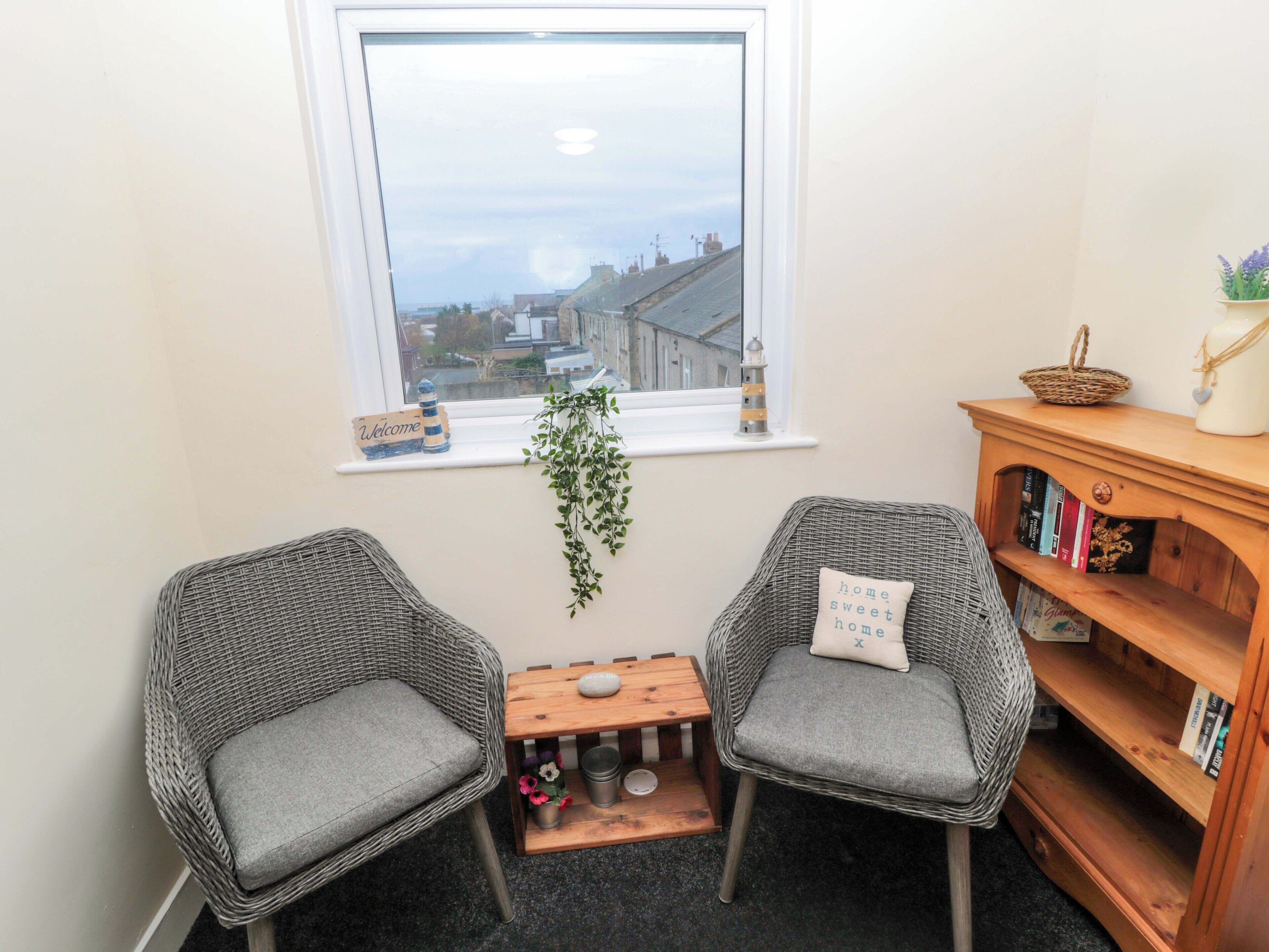 A cozy corner with two wicker chairs, a small wooden table, and a bookshelf.
