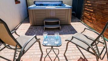 A hot tub with a table and two chairs in a patio area.