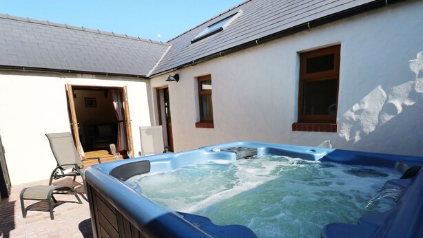 Ein Whirlpool in einem Außenbereich mit einer Ziegelterrasse und einem weißen Gebäude im Hintergrund.