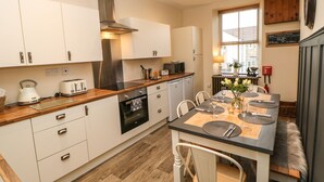 A modern kitchen with white cabinets, a wooden countertop, and a built-in oven. - Magnolia Cottage (Richmond)