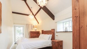 Une chambre à coucher avec un lit en bois, des tables de chevet, un lustre et une fenêtre.