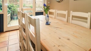 A dining area with a wooden table, white chairs, a wall clock, and a framed picture. - The Old Swan (Malmesbury)
