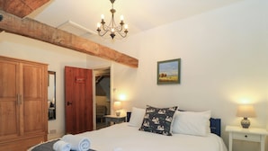 A bedroom with a large bed, wooden wardrobe, and a chandelier. - The Old Swan (Malmesbury)