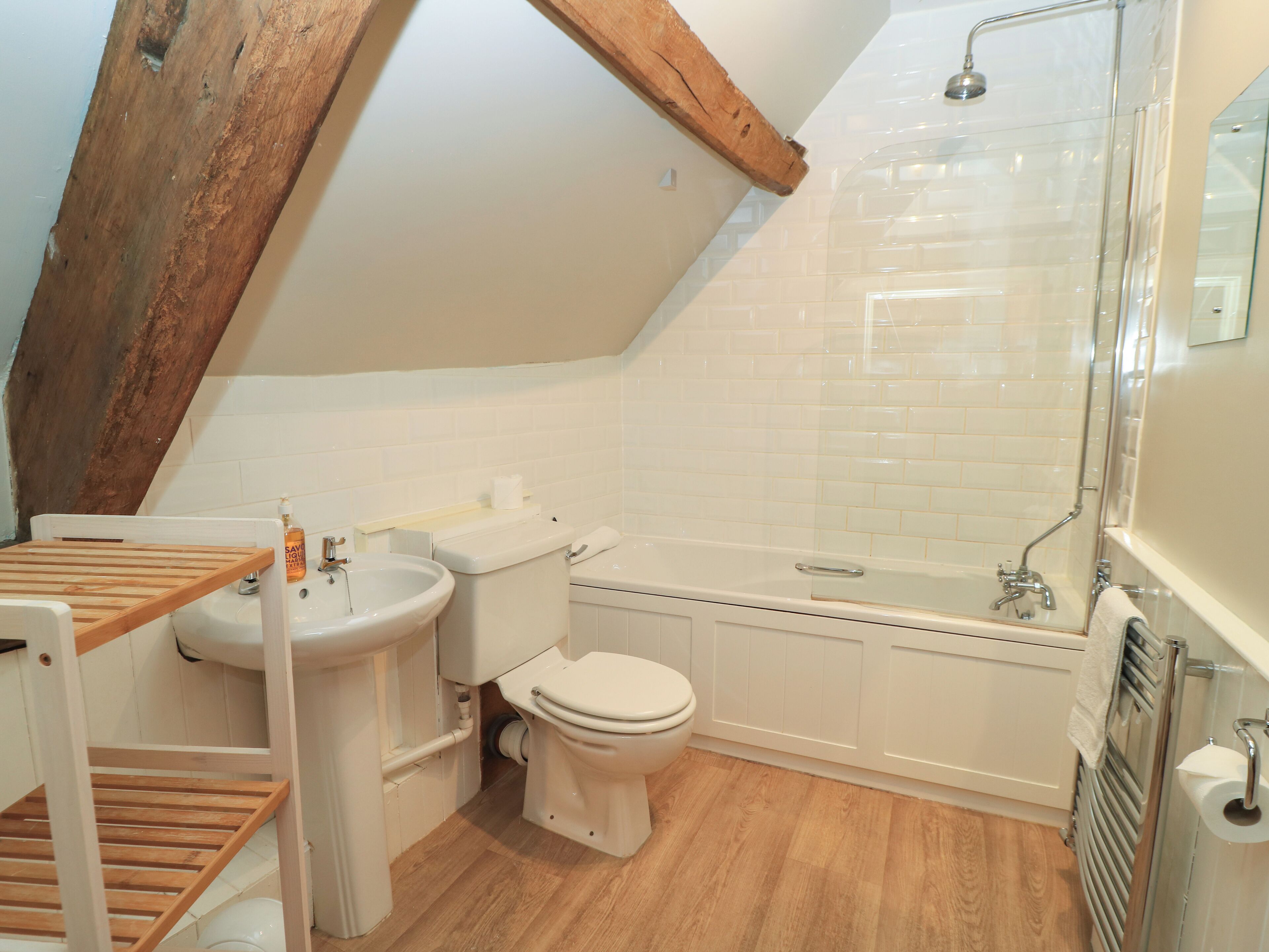 A bathroom with a wooden slatted bench, a sink, a toilet, and a bathtub.