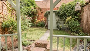 A garden with a brick pathway leading to a wooden gate. - Ploughman's (Diss)