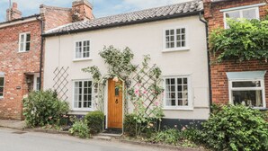 A traditional two-story house with a wooden front door, white-framed windows, and a brick exterior. - Ploughman's (Diss)
