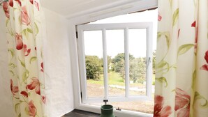 Una ventana con marco blanco y un florero verde en el alféizar.