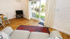 Un salón acogedor con sofá, televisor y vista al exterior a través de un ventanal.