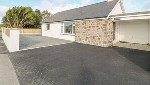 A two-story house with a stone facade, a garage, and a paved driveway. - Trem Y Garn (Pwllheli)