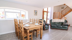 A dining area with a wooden table and chairs, a green leather sofa, and a staircase.