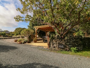 Relax beneath a rustic pergola in a secluded garden area surrounded by potted plants.