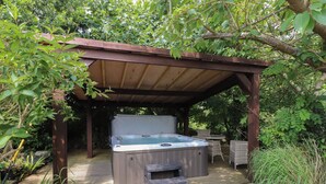 A hot tub under a wooden pergola surrounded by greenery. - Plas Mawr (Caernarfon)
