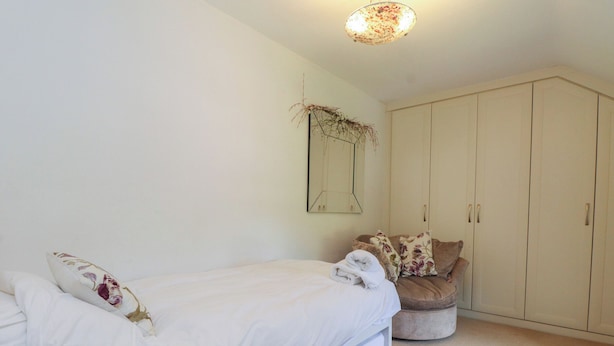 A bedroom with a bed, a chest of drawers, a round ottoman, and a mirror on the wall. - Plas Mawr (Caernarfon)