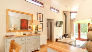 A well-lit room with a wooden cabinet, a mirror, a television, and a fireplace. - Seaton (Oakham)