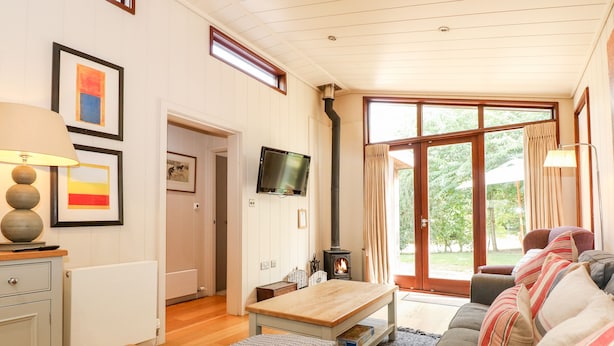 A cozy living room with a fireplace, a television, and a sofa with cushions. - Seaton (Oakham)