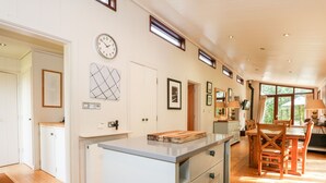 A spacious kitchen with a central island, wooden flooring, and a dining area with natural light. - Seaton (Oakham)