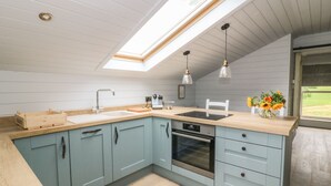 Una cocina moderna con tragaluz, armarios azul claro, encimera de madera y vistas al exterior.