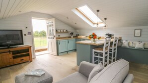 Un espacio habitable y cocina integrados, acogedor, con televisor, sofá y mesa de comedor.