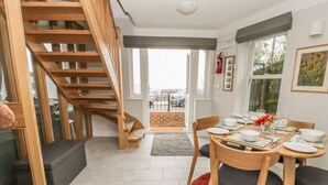Eine moderne Küche mit einer Holztreppe, einem Essbereich mit einem roten Teppich und Blick ins Freie.