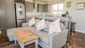 A modern kitchen with grey cabinets, a built-in oven, and a stainless steel refrigerator. - Emblestones (Alnwick)