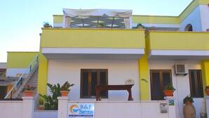 A two-story building with a yellow facade, a staircase, and potted plants. - B&B Barone (Castro)