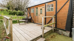 A wooden cabin with a deck, a door, and windows. - Railway Carriage (Abergavenny)
