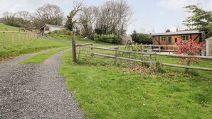 A rural property with a gravel path leading to a wooden gate, surrounded by green fields and trees. - Railway Carriage (Abergavenny)