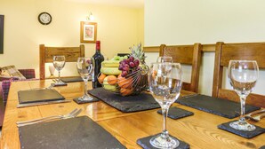 A dining table set with wine glasses, cutlery, and a fruit basket. - Y Bwthyn (Tywyn)