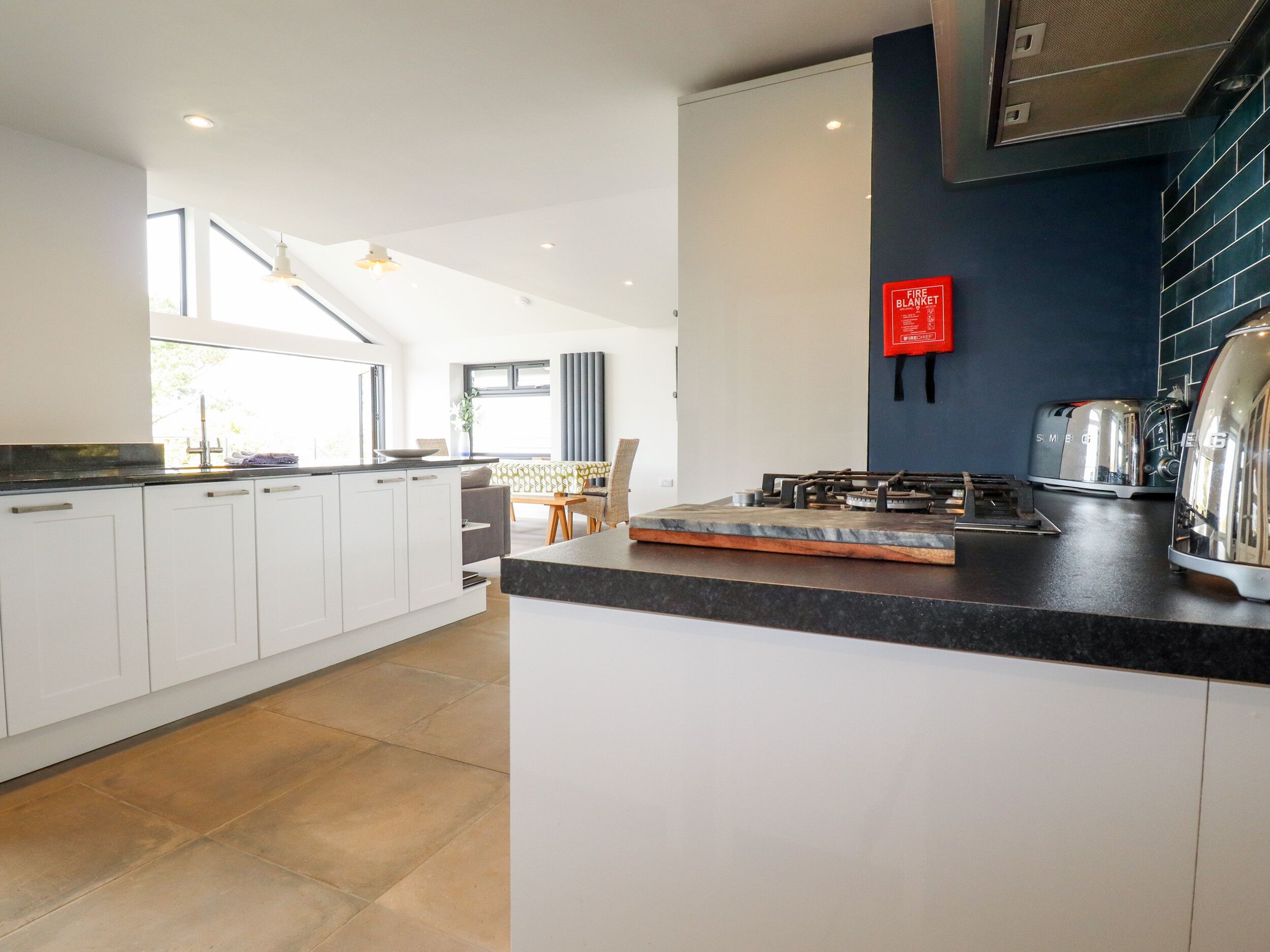 A modern kitchen with white cabinets, a black countertop, and stainless steel appliances.