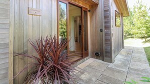 Una casa moderna de madera con un amplio ventanal, un pequeño espacio al aire libre con una planta, y un letrero que dice "Chipsham".
