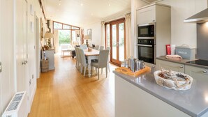 Una cocina amplia con electrodomésticos modernos, un comedor con una mesa grande y vistas al exterior a través de las ventanas.