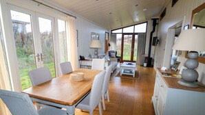 Uma sala de jantar espaçosa com uma mesa de madeira, cadeiras brancas, um sofá e um abajur.